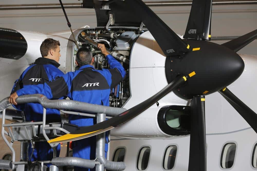 Two aircraft technicians inspecting a ATR engine in a hangar.
